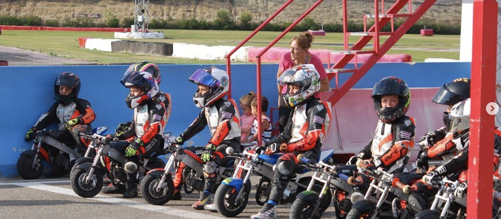 Alumnos de la escuela, con equipación completa, esperando en pista sobre sus minimotos