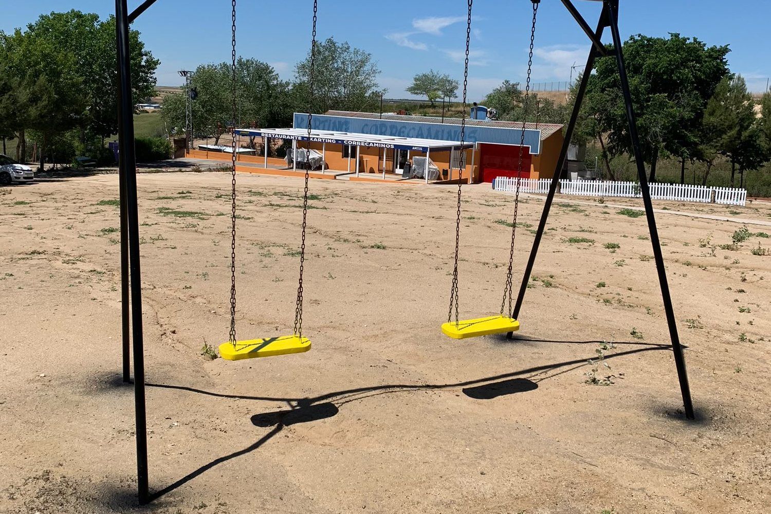 Columpios del parque infantil, con el restaurante al fondo